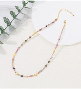 Detalle de collar artesanal de turmalina con dijes de corazón dorado y cierre ajustable