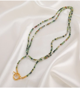 Dettaglio di perle in pietra naturale verde con elegante chiusura a barra dorata