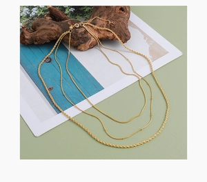Detalle de collar multicapa dorado con cadena de serpiente y cuerda sobre madera