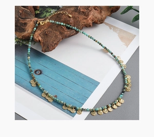 Detalle del collar bohemio de cuentas turquesas con colgantes de discos dorados