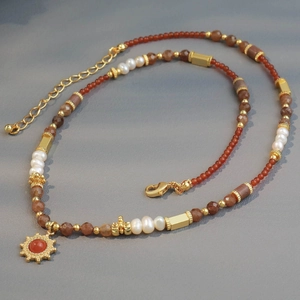 Ethnic pearl necklace with natural stones and sun pendant on a textured background