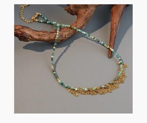 Detalle de collar de cuentas turquesas con borlas doradas sobre madera rústica