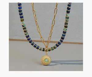 Close-up of double-layered beaded necklace featuring a gold sunflower pendant and stones