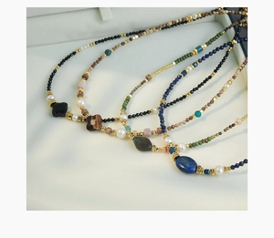 Detalle del collar hecho a mano con ojo de tigre, lapislázuli y perlas naturales
