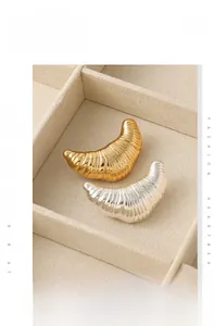 Detail showing metallic croissant-shaped stud earrings in polished gold and silver finishes