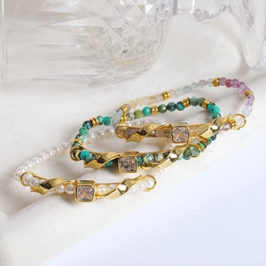 Detalle de tres pulseras de perlas, turquesa y dijes dorados con circonitas brillantes