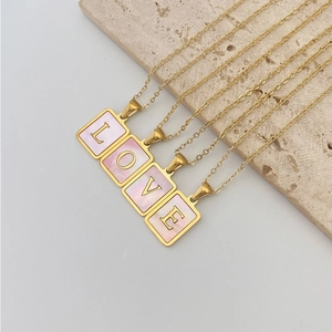 Nahaufnahme der goldenen quadratischen Anhänger mit rosa Muschel und L-O-V-E Buchstaben