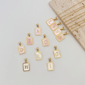 Makroaufnahme goldener quadratischer Buchstabenanhänger mit Einlagen aus Perlmutt