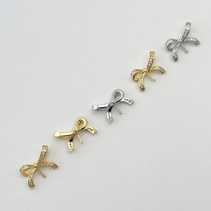 Detailed macro view of bow-shaped jewelry components with pavé zircon in gold and silver