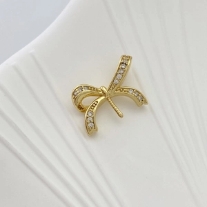 Detailed view of a gold bow pendant with micro-paved sparkling cubic zirconia crystals