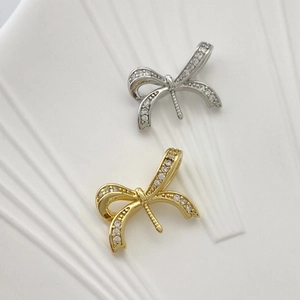 Macro detail of micro-pave zircon bow pendants in gold and silver plating on ceramic