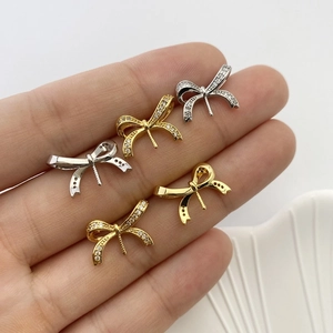 Macro detail of micro-pave zircon bow pendant bases for DIY jewelry in gold and silver
