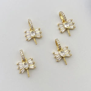 Macro detail of four gold bow-shaped zircon pendants for DIY jewelry making and crafts