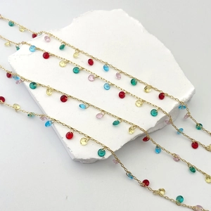 Macro shot of 18K gold chain with vibrant multi-colored zirconia beads on a white stone