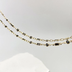 Detailed close-up of golden chain with emerald-cut black zircon for DIY jewelry making