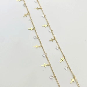 Macro detail of gold chains with delicate cross pendants and square zircon crystals