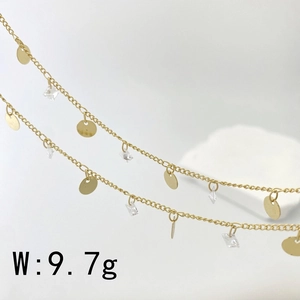 Macro detail of gold plated chain with square clear crystals and round metal charms