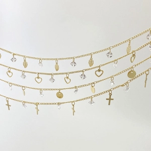 Detail of gold chain jewelry set featuring leaf, heart, and cross zircon pendants