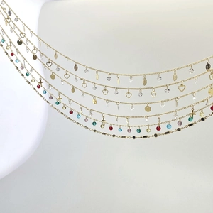 Detailed close-up of golden multilayer chains with colorful zircon beads and exotic charms