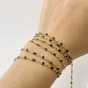 Detailed view of a gold chain bracelet featuring black rectangular zircon stones on a wrist