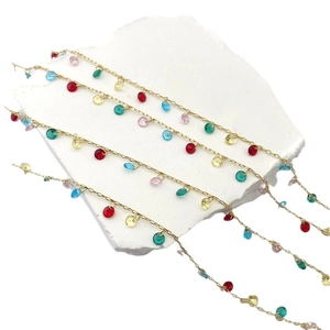 Golden chain necklace with colorful round zircon pendants on white stone background