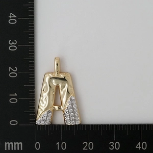 Macro shot showing dimensions of letter A pendant with zircons on a millimeter scale
