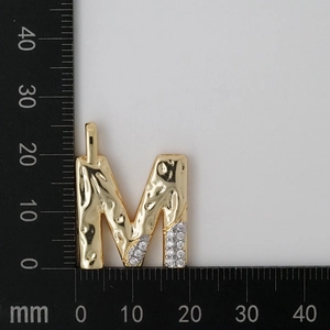 Detail of gold letter M pendant with hammered texture and white cubic zirconia accents