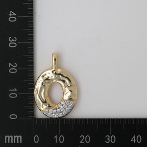 Detailed macro view of gold hammered oval pendant with cubic zirconia inlay and scale measure