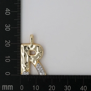 Detailed measurement of gold letter R pendant with cubic zirconia inlay on grey background