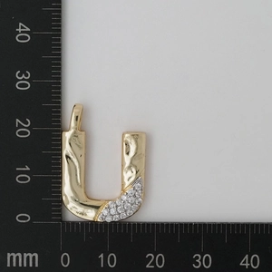 Detailed view of two-tone letter U pendant with gold lava texture and sparkling zircons