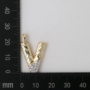 Macro shot of gold V-shaped letter pendant with zircon stones and size measurements