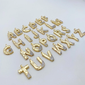 Macro view of 26 alphabet letter pendants with hammered gold texture and pave zircon