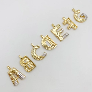Detailed close-up of lava textured gold letter pendants with micro-paved cubic zirconia