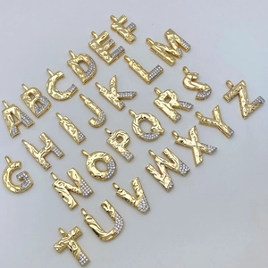Detailed close-up of gold plated lava texture alphabet pendants with zircon inlay
