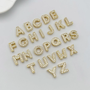 Macro view of 26 gold-plated alphabet charm beads with cubic zirconia for DIY jewelry