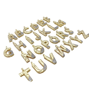 Golden hammered letter pendants with zircon inlay arranged on white background