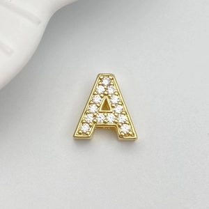 Macro shot of gold letter A charm accessory featuring sparkling white cubic zirconia inlay