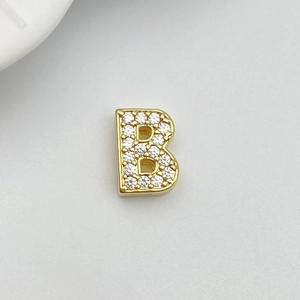Macro view of gold-plated letter B charm with micro-paved white cubic zirconia stones