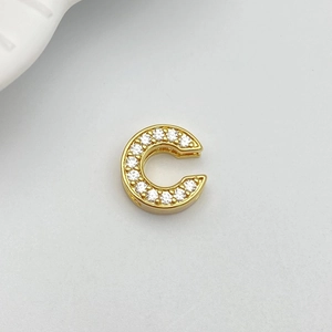 Macro detail of gold-plated letter C pendant with micro-paved white zircon stones