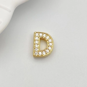 Detailed close-up of golden letter D charm with white zircon micro-pave setting