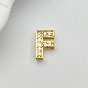 Detailed macro view of gold-plated letter F charm with micro-set white cubic zirconia stones