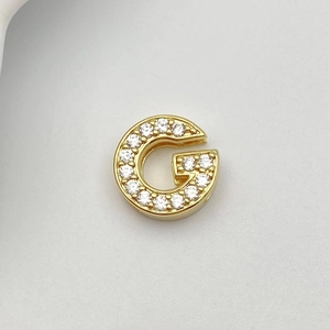 Macro detail of gold G letter pendant with cubic zirconia stones for DIY jewelry
