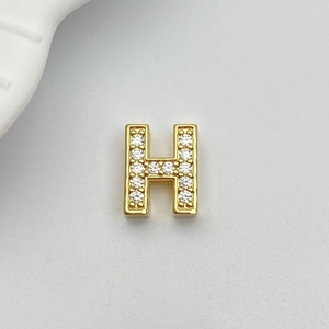 Macro view of gold-plated letter H pendant featuring micro-pave white zircon stones