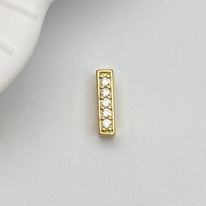 Macro detail of gold-plated rectangular charm set with five sparkling white zircons