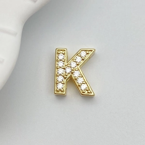 Macro detail of gold letter K charm pendant with sparkling white cubic zirconia stones
