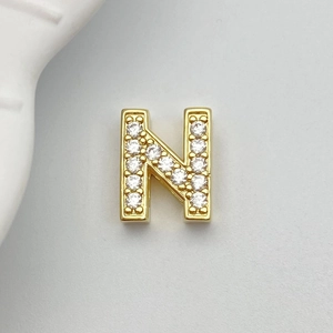 Detailed macro view of gold-plated letter N jewelry charm with white zircon inlay