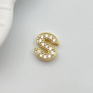 Detailed macro view of a gold-plated letter S charm with sparkling white zircon stones