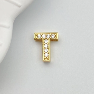 Macro detail of gold-plated letter T charm with ten sparkling white zircon stones