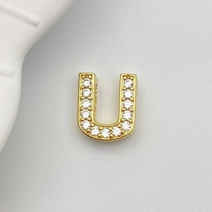 Detailed macro view of gold-plated U-shaped charm with pavé white cubic zirconia stones