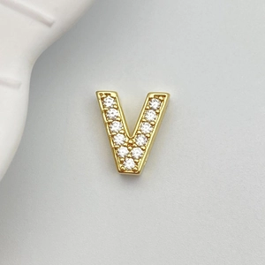 Detailed close-up of golden letter V charm with white zircons for DIY jewelry